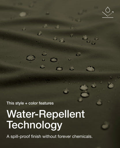 Close up view of draped Jaanuu fabric in Deep Olive with water beading on the surface. Text on the image reads "This style + color features Water-Repellent Technology. A spill-proof finish without forever chemicals."