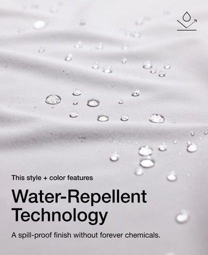 Close up view of draped Jaanuu fabric in White with water beading on the surface. Text on the image reads "This style + color features Water-Repellent Technology. A spill-proof finish without forever chemicals."
