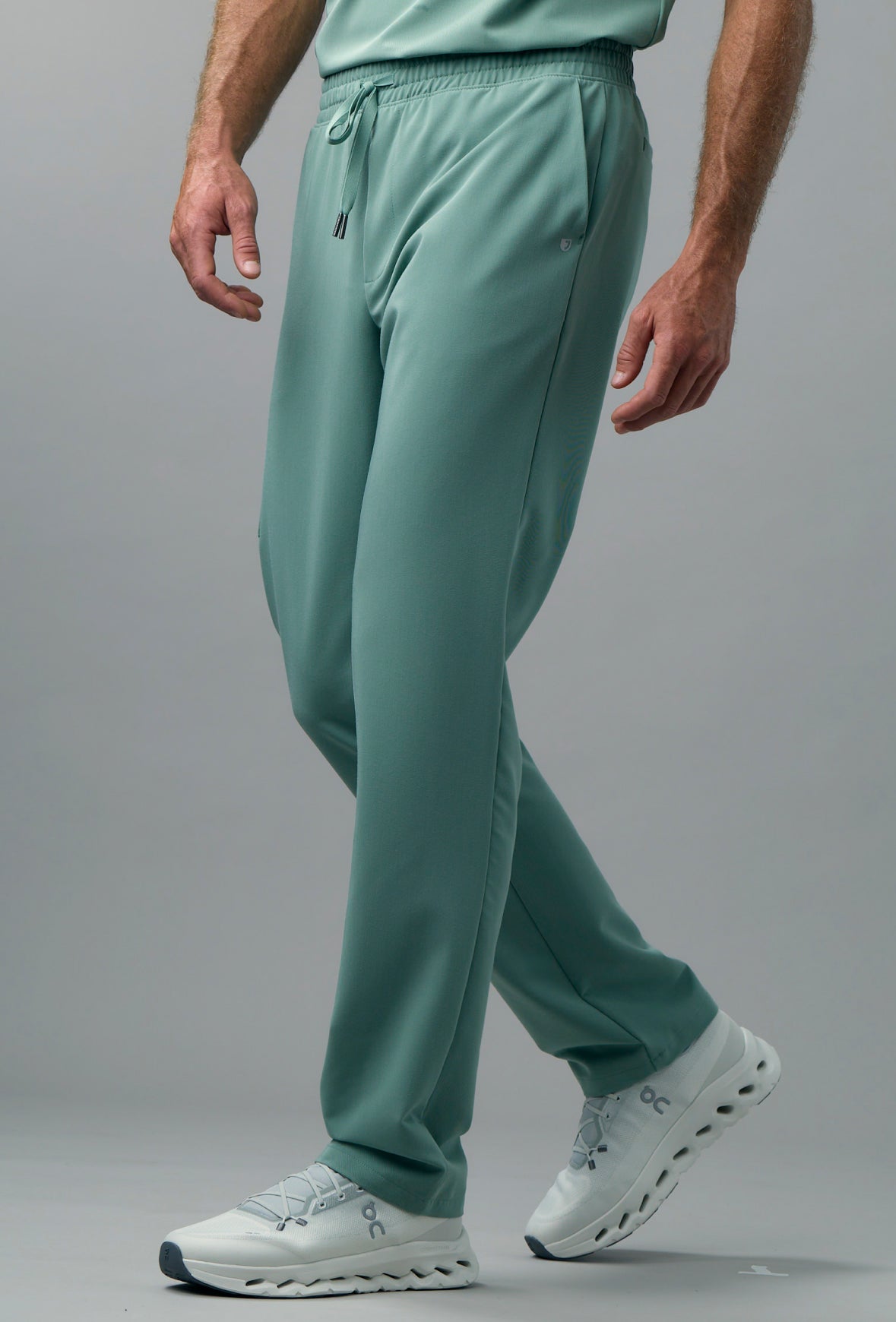 Man in green scrub pants and white sneakers mid-stride