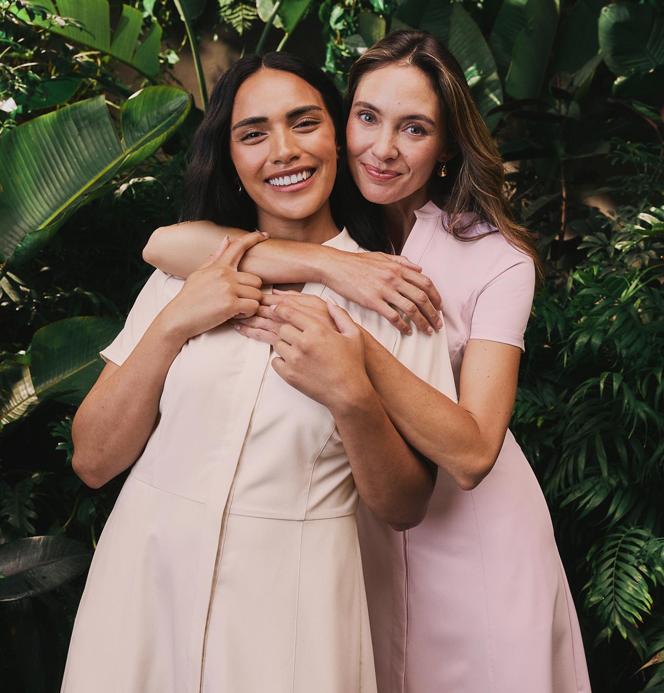2 women wearing scrubs hugging each other.