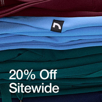 A stack of folded scrubs and scrub jackets stacked on top of each other. Image has text, "20% Off Sitewide". - Women Nav Tile
