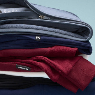 Image of folded JAANUU jackets stacked on top of each other. - Women Nav Tile