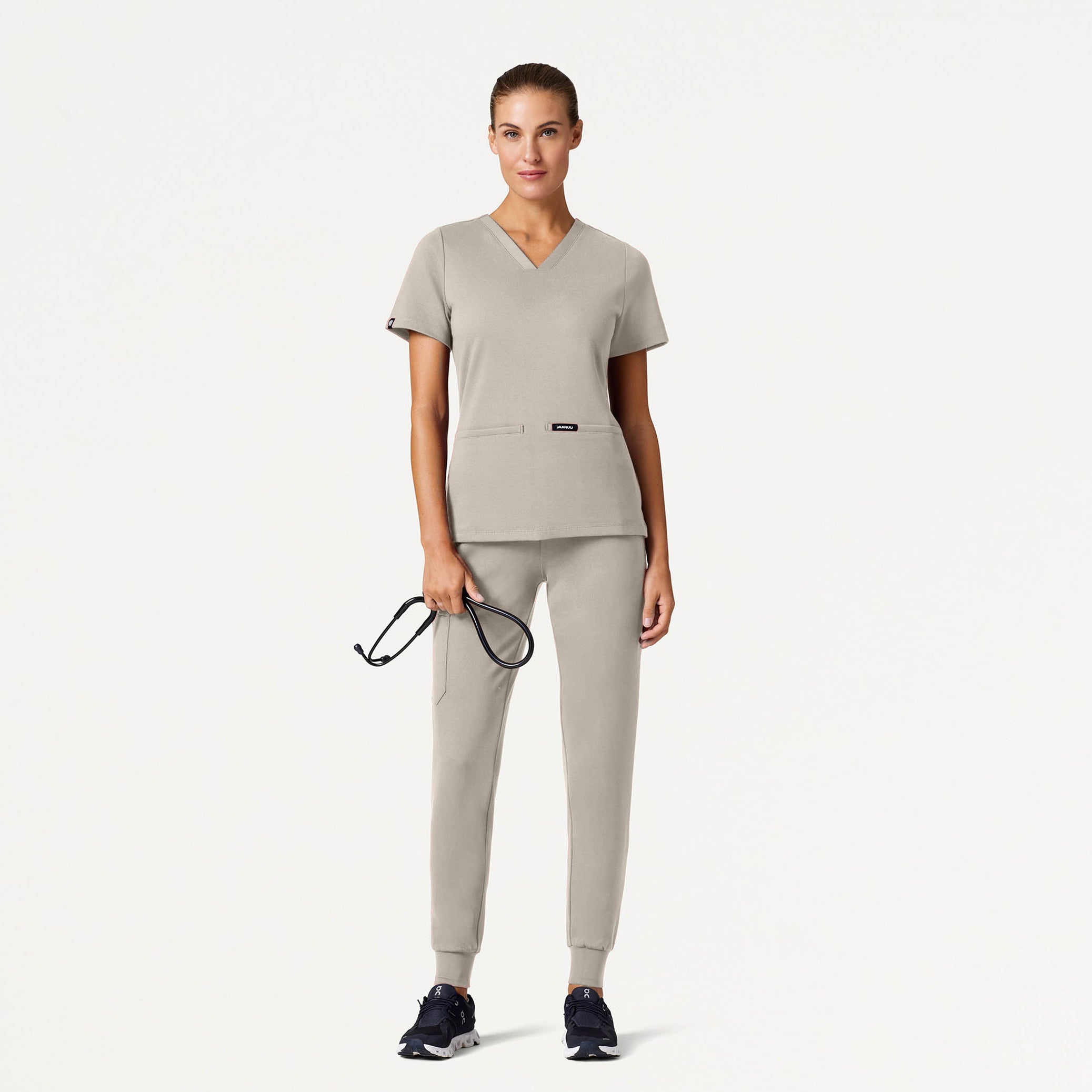 Woman wearing Fog color scrub set holding a stethoscope.