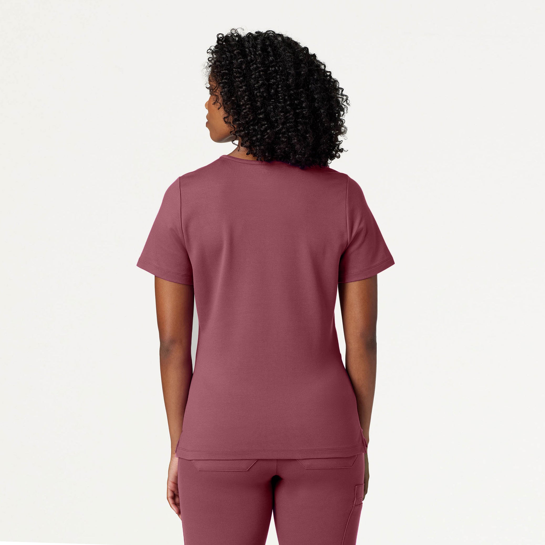 Person wearing a Rosewood scrub top and pants on a white background