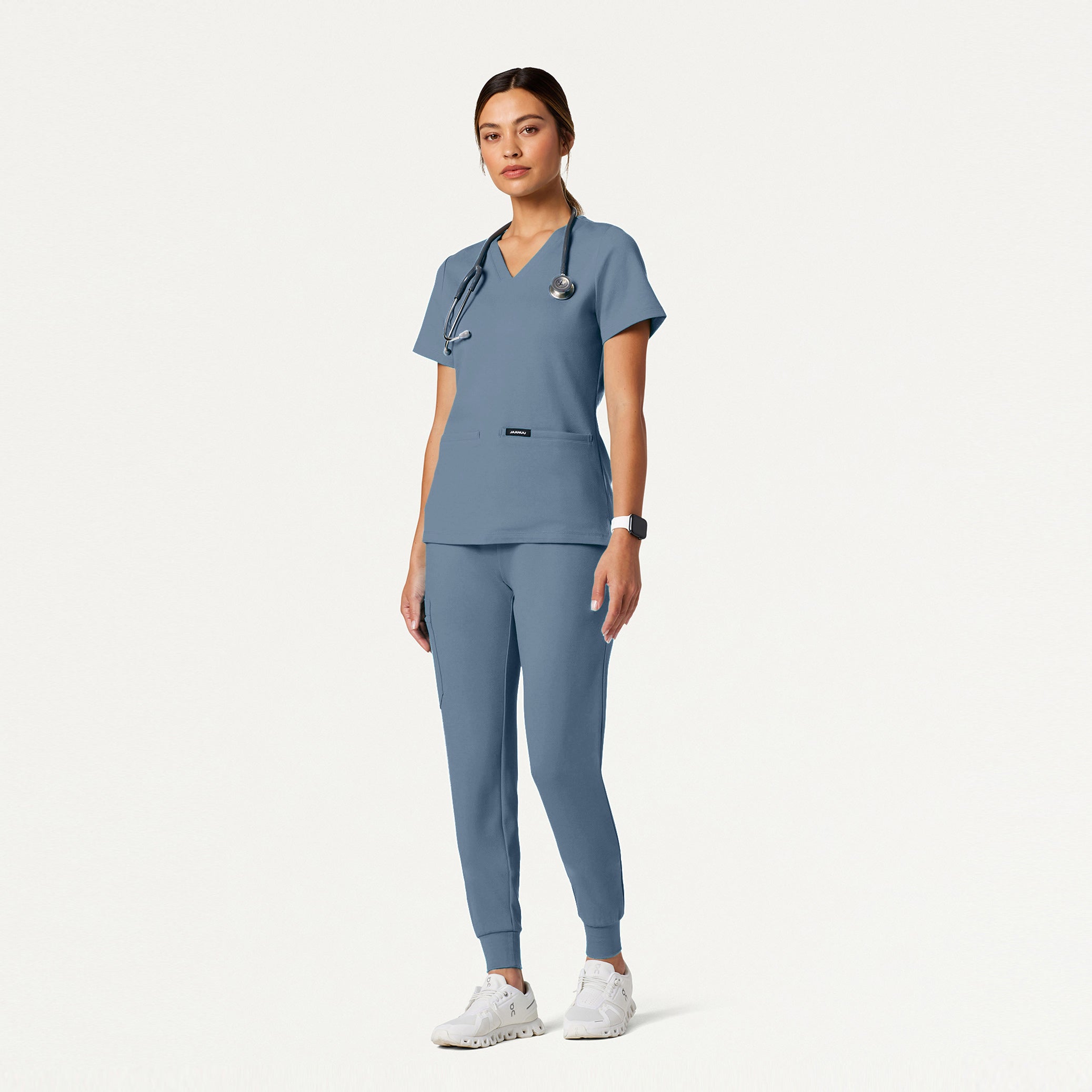 Person wearing a Storm Blue scrub set with a stethoscope on a white background