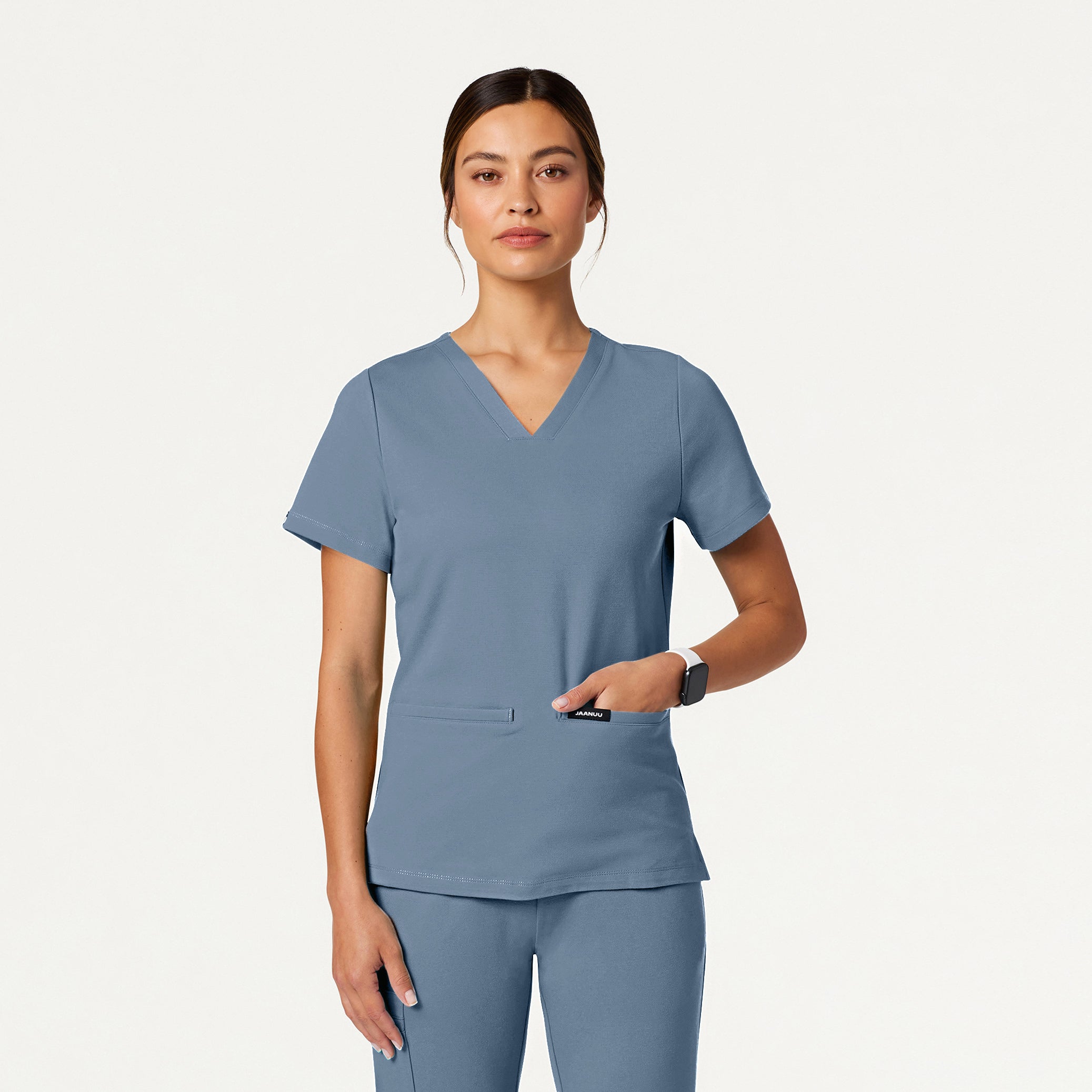Woman wearing a Storm Blue scrub set on a white background