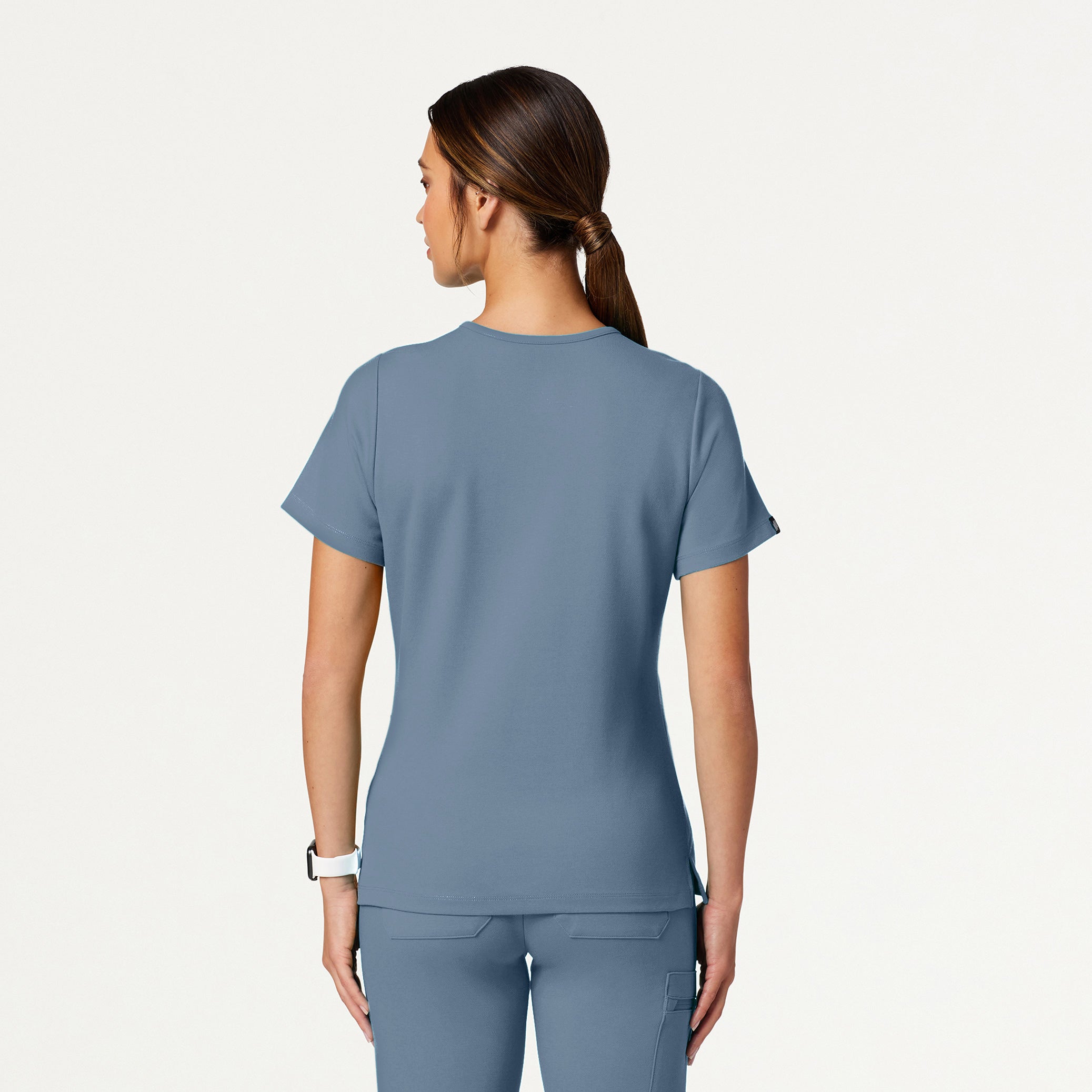 Woman wearing a Storm Blue scrub set on a white background