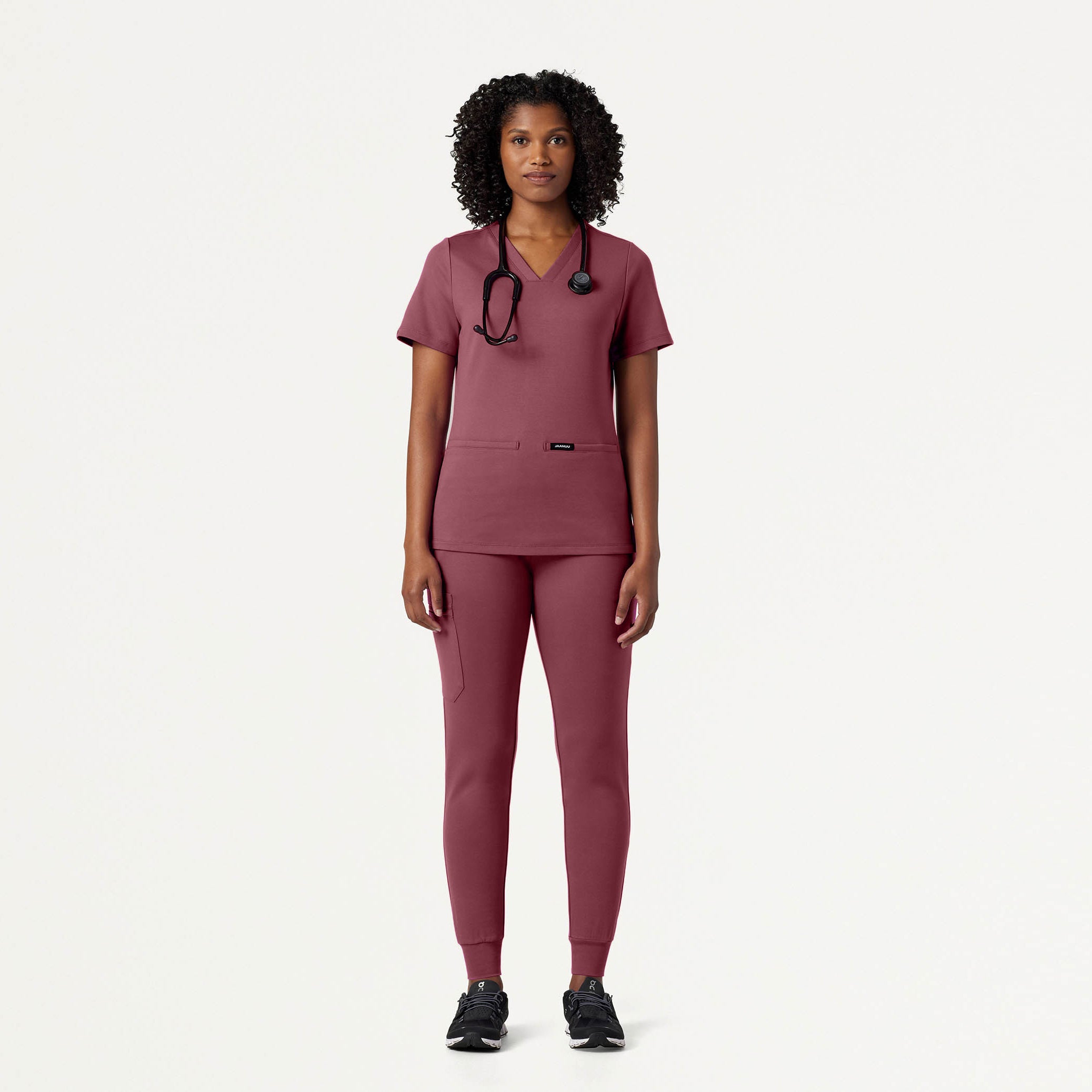 Person wearing a Rosewood scrub set with a stethoscope on a white background