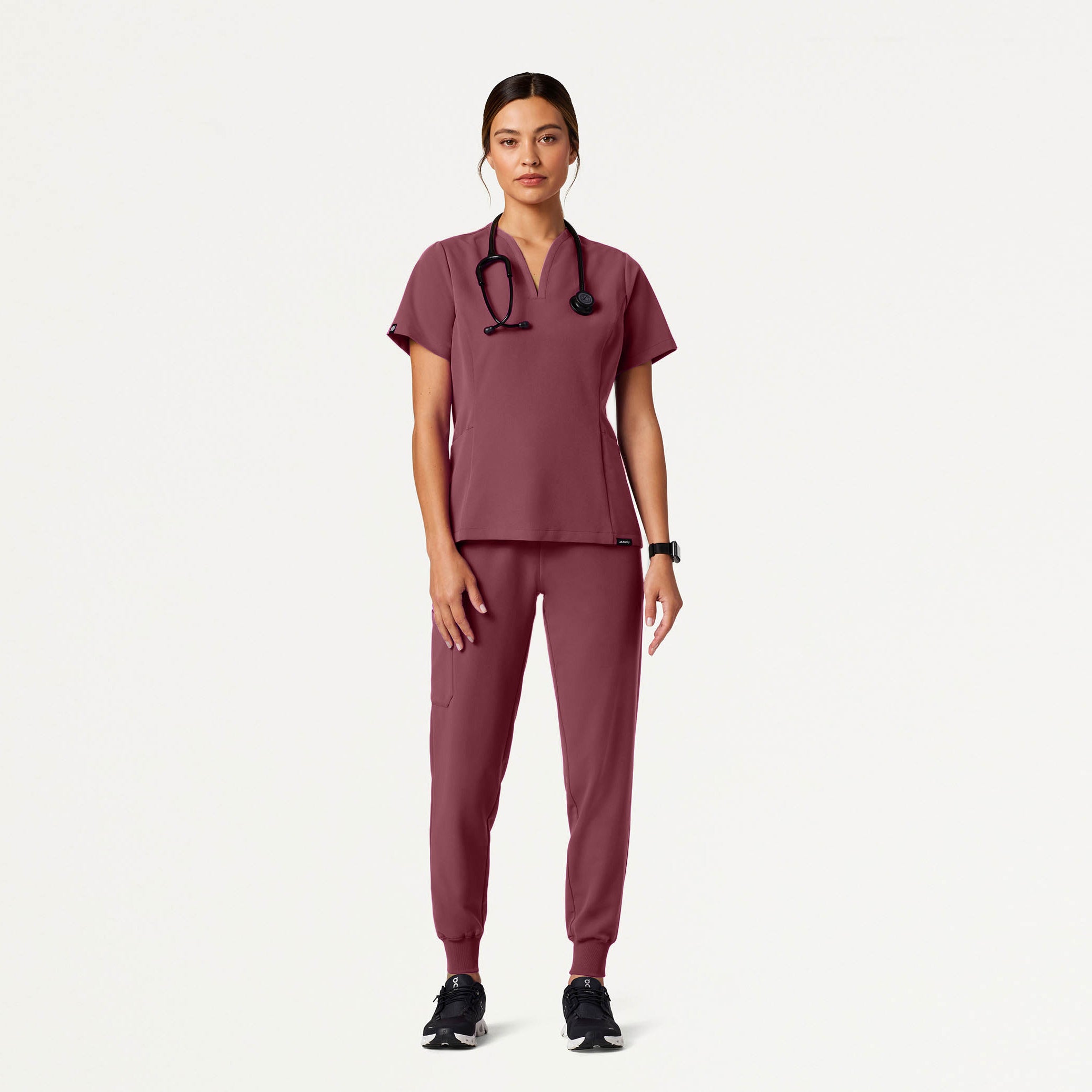 Person wearing a Rosewood scrub set with a stethoscope on a white background