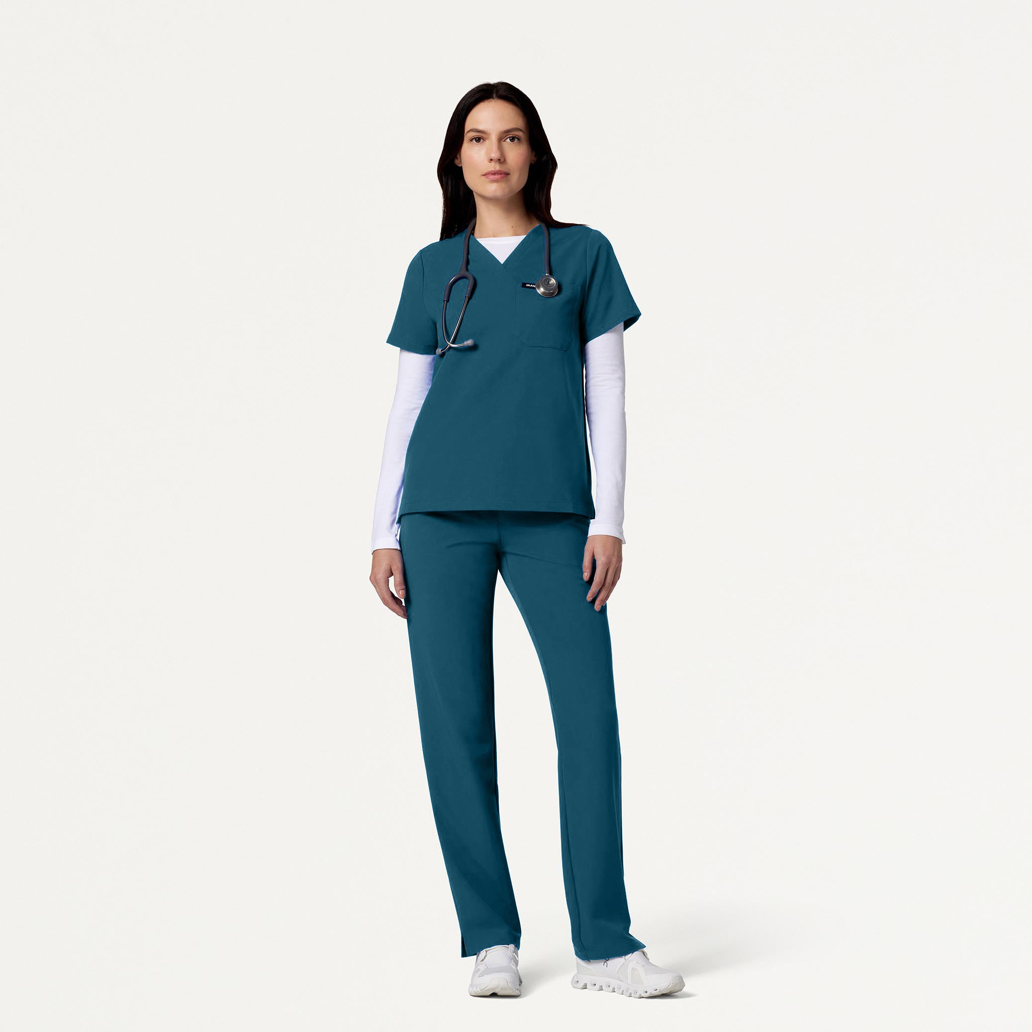 Woman wearing Caribbean Blue scrubs with white underscrub