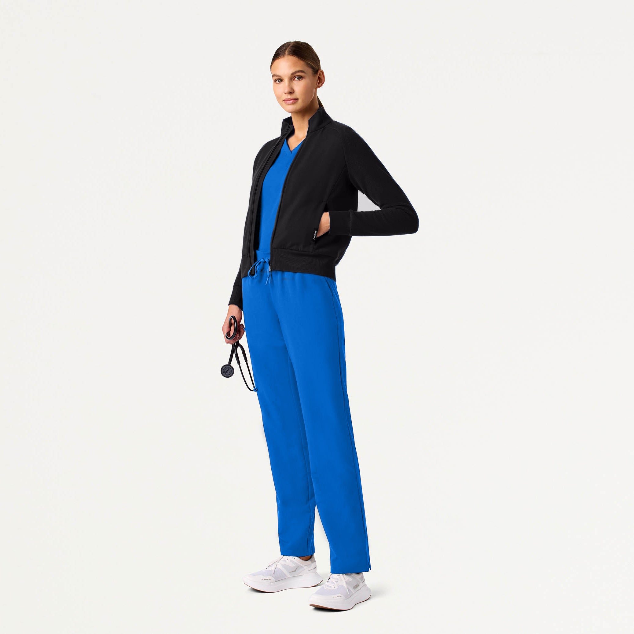 Woman wearing a black jacket and blue pants on a white background