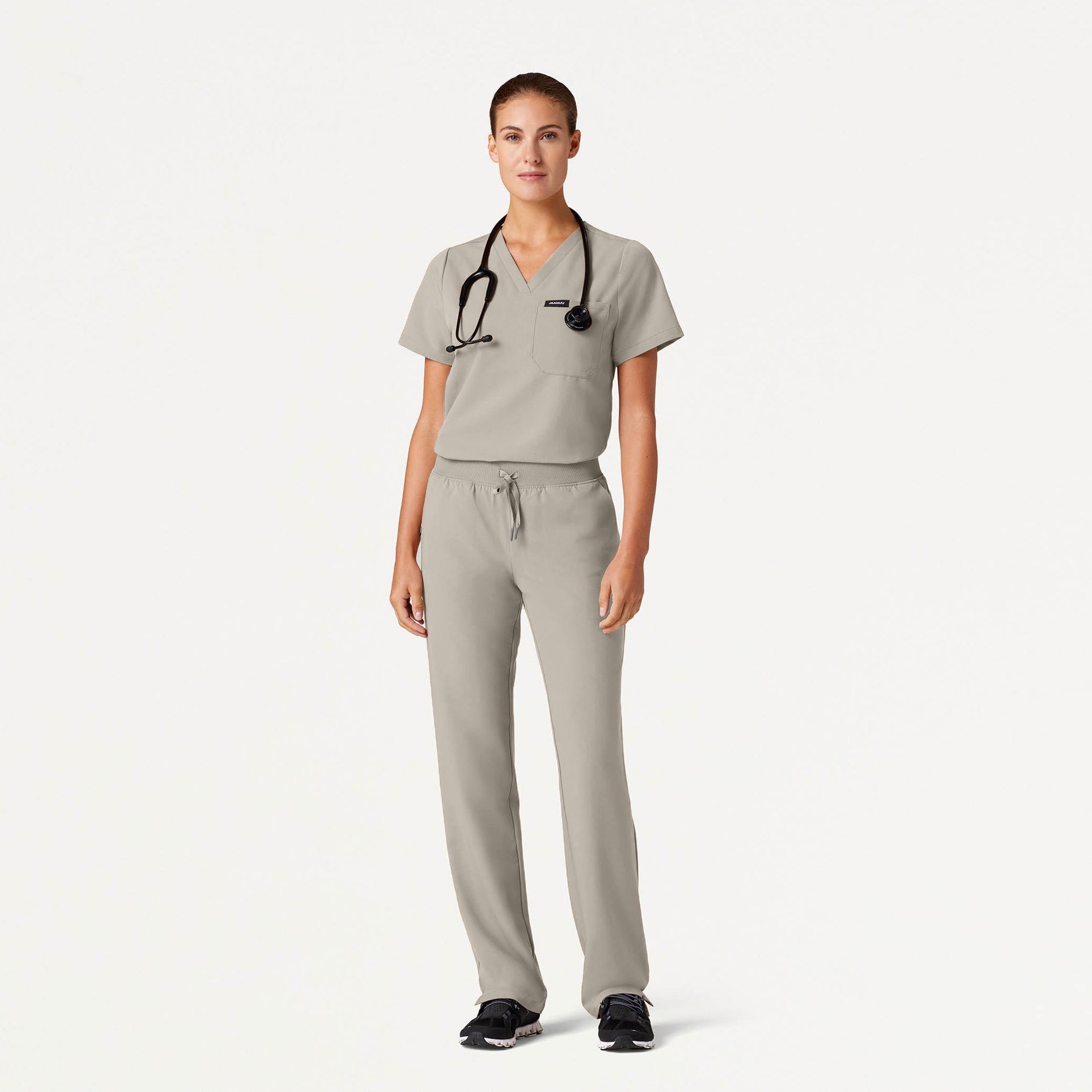 Person wearing a gray scrub set with a stethoscope on a white background